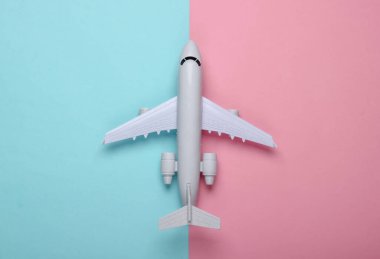 Mavi-pembe pastel arka planda uçağın oyuncak modeli. Turizm, hava yolculuğu, minimalizm. Üst görünüm