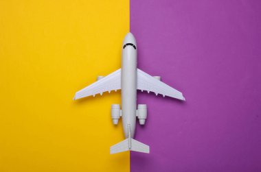 Mor sarı arka planda uçağın oyuncak modeli. Turizm, hava yolculuğu, minimalizm. Üst görünüm
