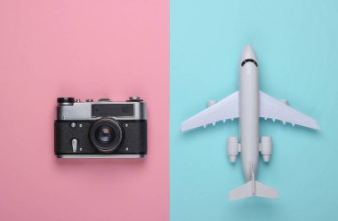 Pembe mavi pastel arka planda düz seyahat kompozisyonu. Uçak figürü ve film kamerası. Eğlence, tatil ve turizm, minimalizm konsepti. Üst görünüm