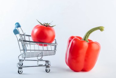 Beyaz arka planda dolmalık biberli ve domatesli alışveriş arabası. Süpermarket kavramı