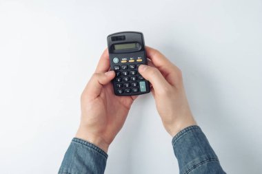 Beyaz arkaplandaki bir hesap makinesinde erkek eller sayılıyor