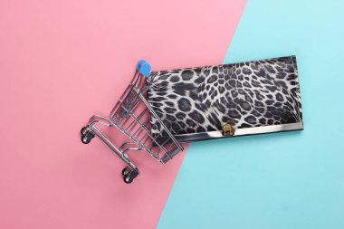 Mavi pembe pastel arka planda cüzdanı olan bir alışveriş arabası. Üst Manzara. Minimalizm alışveriş konsepti. Düz yatıyordu