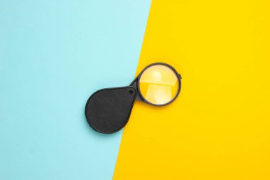 Sarı-mavi pastel arka planda cep büyüteci. Üst görünüm