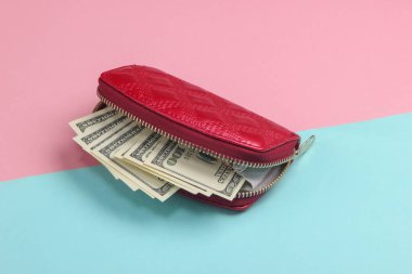 Kırmızı cüzdan ve mavi-pembe renkli arka planda 100 dolarlık banknotlar..
