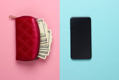 Kırmızı cüzdan, yüz dolarlık banknotlar ve mavi-pembe pastel arka planda bir akıllı telefon. Üst görünüm