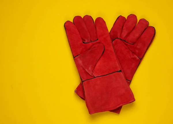 Red work gloves on yellow background. Top view.