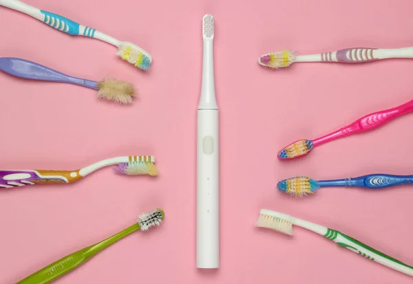 Moderne Elektrische Zahnbürste Und Alte Gebrauchte Zahnbürsten Auf Rosa Pastellgrund — Stockfoto