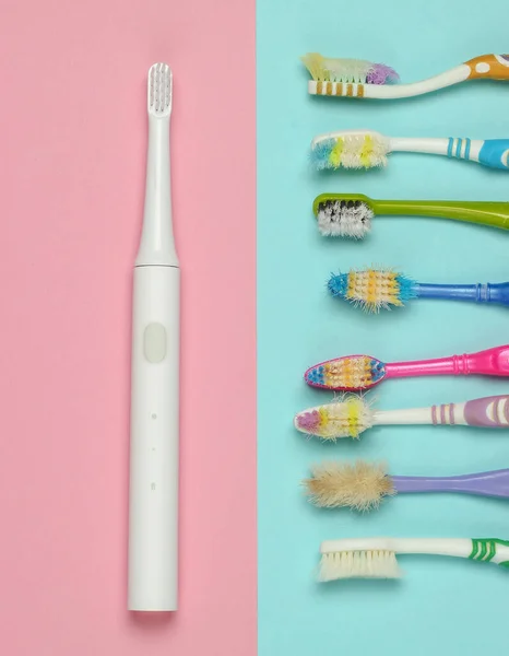 Moderne Elektrische Zahnbürste Und Alte Gebrauchte Zahnbürsten Auf Rosa Blauem — Stockfoto