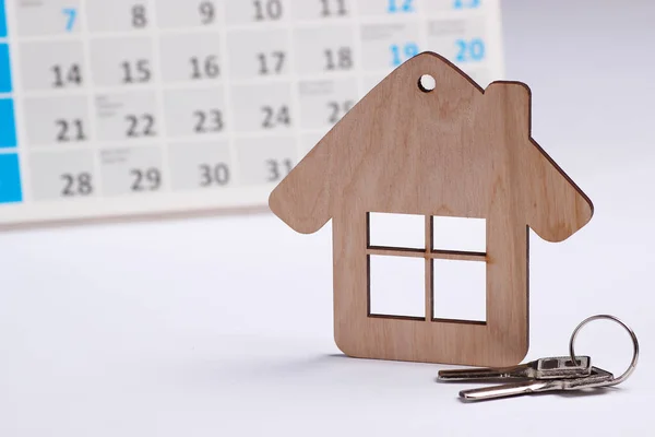 Mini figure house with desktop calendar on white background. Housing rent payment concept
