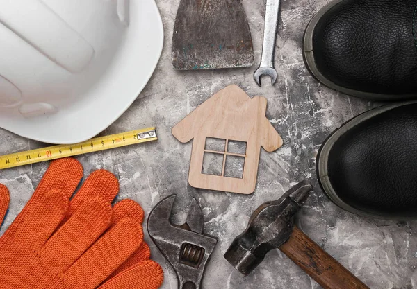 DIY home tool. Construction tools and house figure on gray concrete background. Flat lay composition. Top view