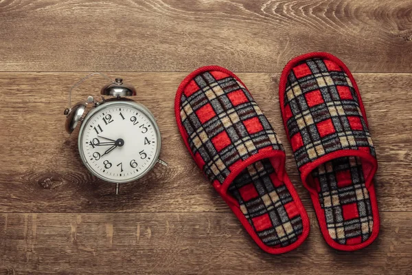 Healthy sleep. Indoor slippers and an alarm clock on the floor. Top view