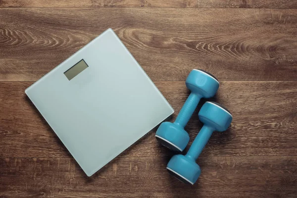 The concept of weight loss, fitness. Floor scales with dumbbells on the floor. Top view