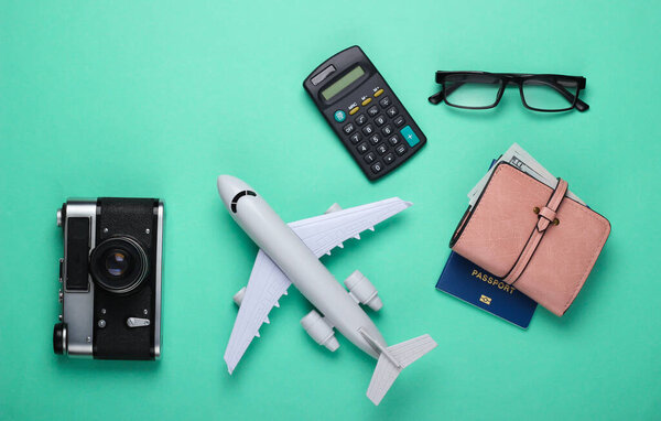 Travel concept. Calculation of the cost of flight and vacation. Plane figurine, camera, wallet, passport and calculator on a blue background. Top view. Flat lay