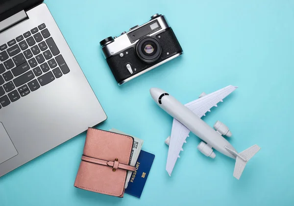 Online ticket booking. Choosing a travel destination. Laptop and airplane figurine, travel accessories on a blue pastel background. Tourism, rest, vacation. Top view