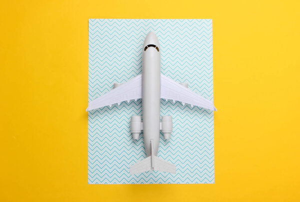 Игрушечная модель плоскости на синем желтом фоне. Концепция туризма, авиаперелетов, минимализм. Вид сверху