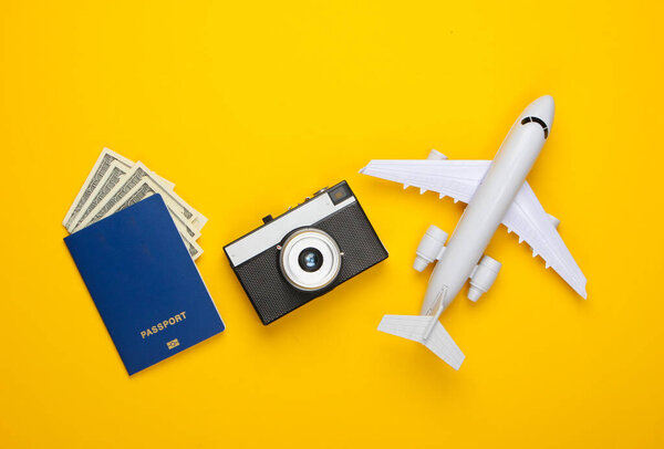 Travel flat lay composition. Plane figurine, camera, passport on a yellow background. Rest, vacation. Top view