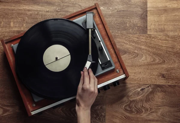 女性の手は木製の床にレトロなビニールレコードプレーヤーを設定します 音楽愛好家 70代 トップビュー — ストック写真