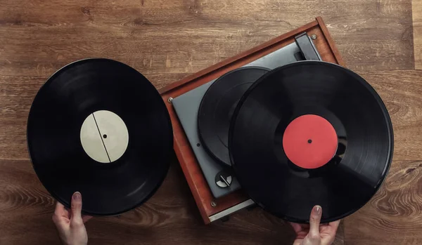 女性の手は木製の床のビニールプレーヤーのためのビニールレコードを拾う 音楽愛好家 70年代 トップビュー — ストック写真