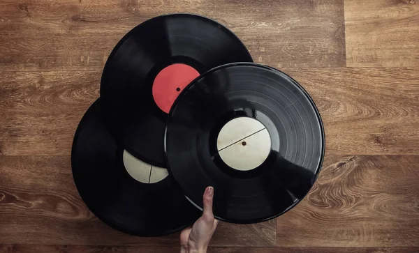 Female Hand Holds Three Vinyl Records Wooden Floor Top View — Stock Photo, Image