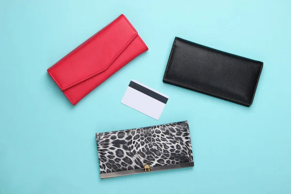 Stylish wallets and bank card on blue background. Shopping concept. Top view