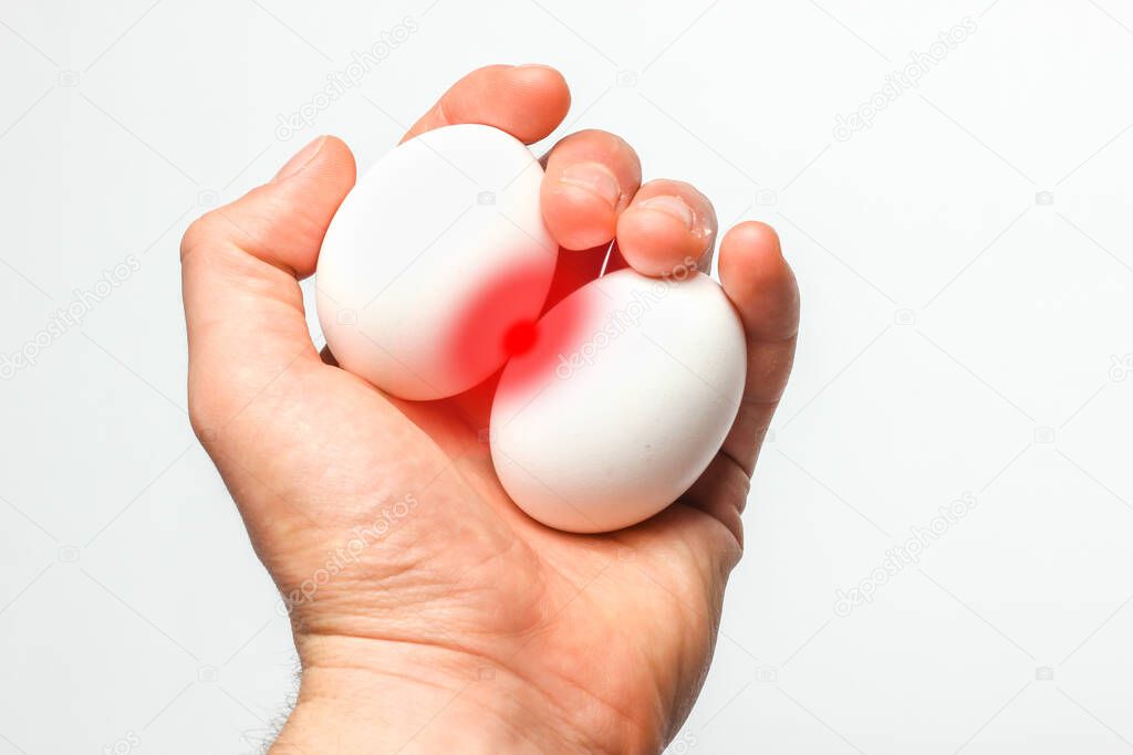 Prostatitis. Inflammation of the prostate. Allegorical photo of chicken eggs with red inflammation in male hands on a white background. Top view