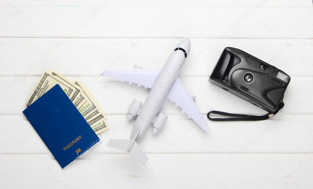 Flat lay design of travel concept with plane, camera and passport. White wooden background. Minimalism. Top view