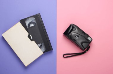 Pembe-mor pastel arka planda video kaset ve retro kamera. Üst görünüm