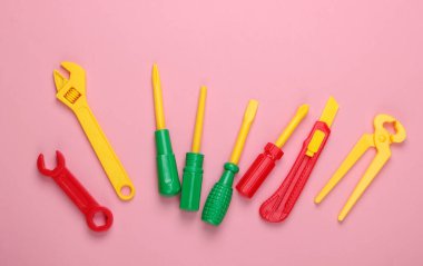 Pembe pastel arka planda çocuk oyuncağı çalışma araçları. Üst görünüm
