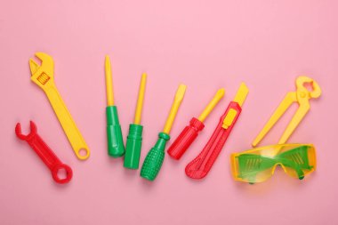Pembe pastel arka planda çocuk oyuncağı çalışma araçları. Üst görünüm