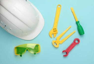 Mavi arka planda çocukların iş aletleri ve kaskları. Üst Manzara. Mühendis, inşaatçı. Çocukluk kavramı