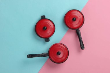 Oyuncak plastik tavalar pembe mavi pastel arka planda. Çocuk Mutfağı. Üst görünüm, minimalizm