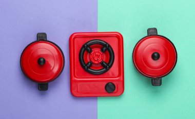 Mor mavi pastel arka planda tavaları olan oyuncak plastik soba. Çocuk Mutfağı. Üst görünüm, minimalizm