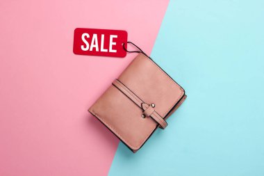 Pembe mavi arka planda kırmızı etiketli şık deri cüzdan. Üst Manzara. İndirim. Minimalizm