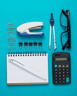 Ofis araçlarının düz kompozisyonu, mavi arka planda kırtasiye malzemesi. Üst görünüm