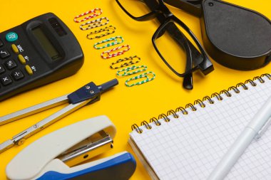 Ofis aletlerinin bileşimi, sarı arka planda kırtasiye malzemesi. Çalışma alanı.