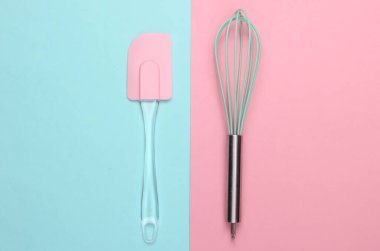 Mutfak spatulası ve pembe mavi pastel arka planda çırpma. Minimalizm. Üst görünüm