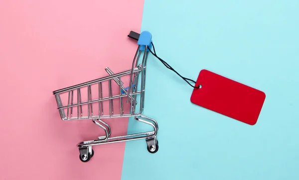 Mini Carrinho Compras Com Etiqueta Vermelha Fundo Pastel Azul Rosa — Fotografia de Stock