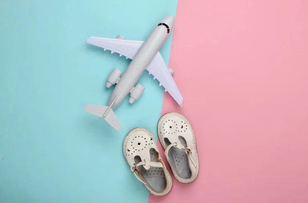 孩子们的凉鞋和玩具飞机平铺在蓝色粉红的粉底上 顶部视图 — 图库照片
