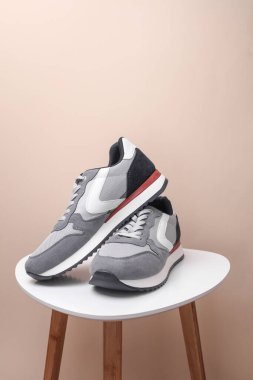 Women's leather sneakers on table, beige background