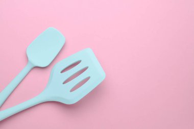 Silicone kitchen spatulas on pink background