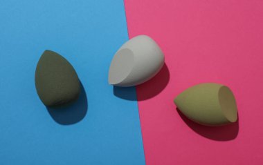 Pembe arkaplanda temel için yumurta makyajı süngerleri