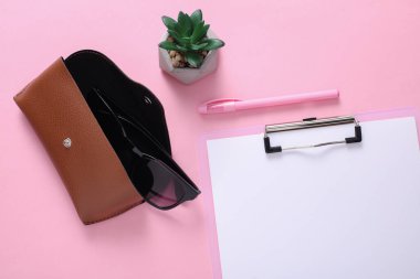 Pembe arka planda güneş gözlüklü deri çanta. Düz yatıyordu