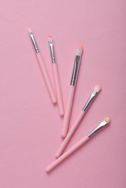 Pembe arka planda makyaj fırçaları