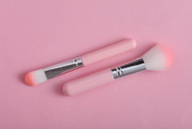 Pembe arka planda makyaj fırçaları