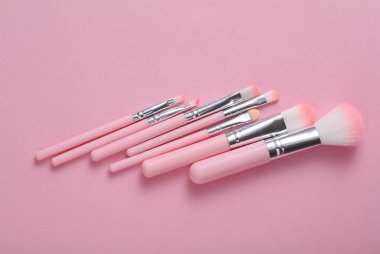Pembe arka planda makyaj fırçaları