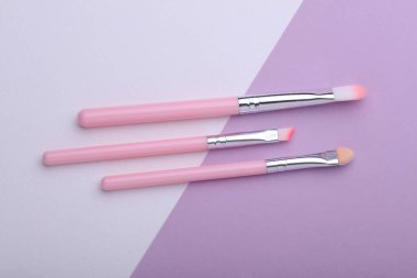 Pink Makeup brushes on purple white background