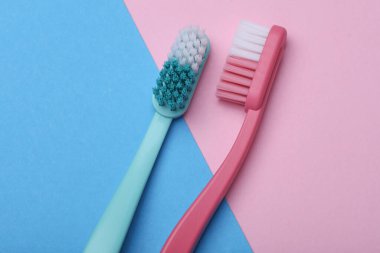 Plastic toothbrushes on blue pink background