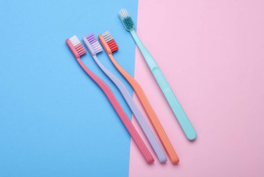Plastic toothbrushes on blue pink background