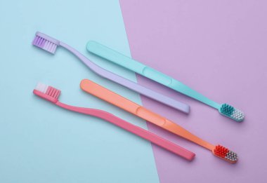 Plastic toothbrushes on pastel background. Top view