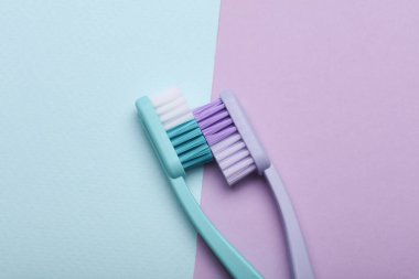 Plastic toothbrushes on pastel background. Top view